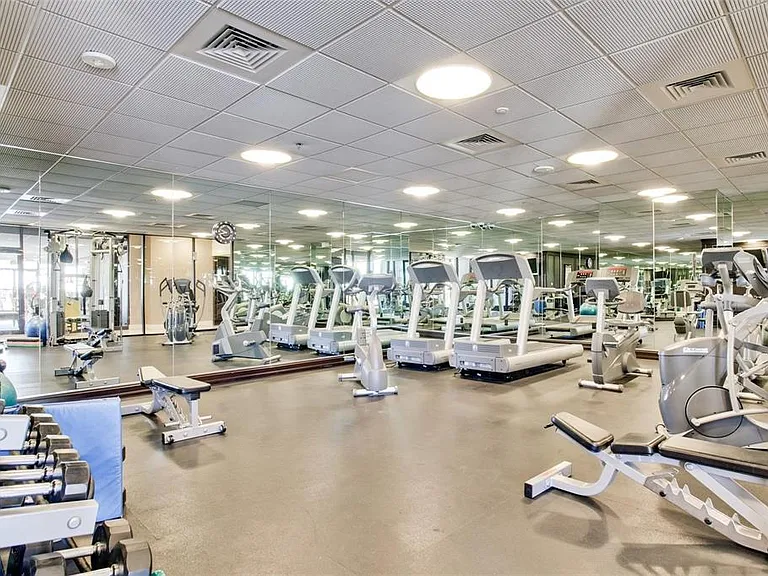 Spacious fitness center featuring a variety of cardio equipment, strength training machines, free weights, full-wall mirrors, and recessed ceiling lighting