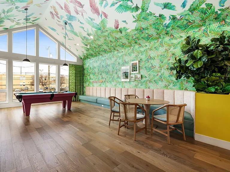 Open-concept room featuring vaulted ceilings with accent wallpaper, wood-finish flooring, and expansive windows