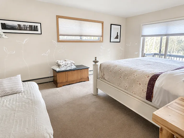 Second primary bedroom with king size bed, balcony out back and en suite bathroom. Pictured on left is a twin mattress from lower level bedroom.