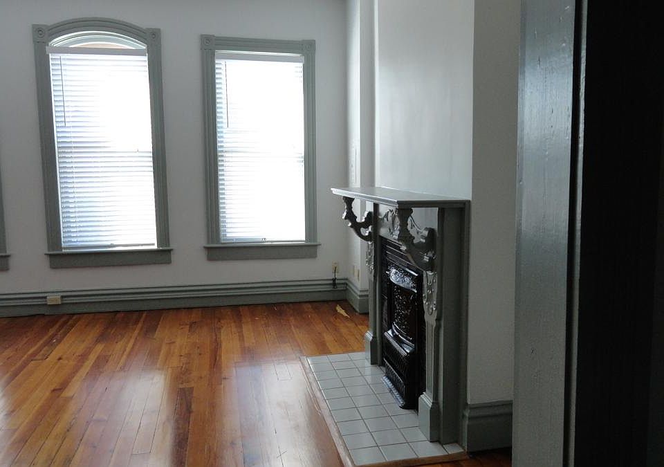 Large living room with four windows, beautiful hardwood floors, fireplace.