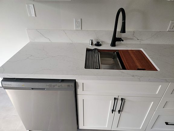 Stainless sink with cutting board, strainer, and other accessories. New Moen pull down faucet.