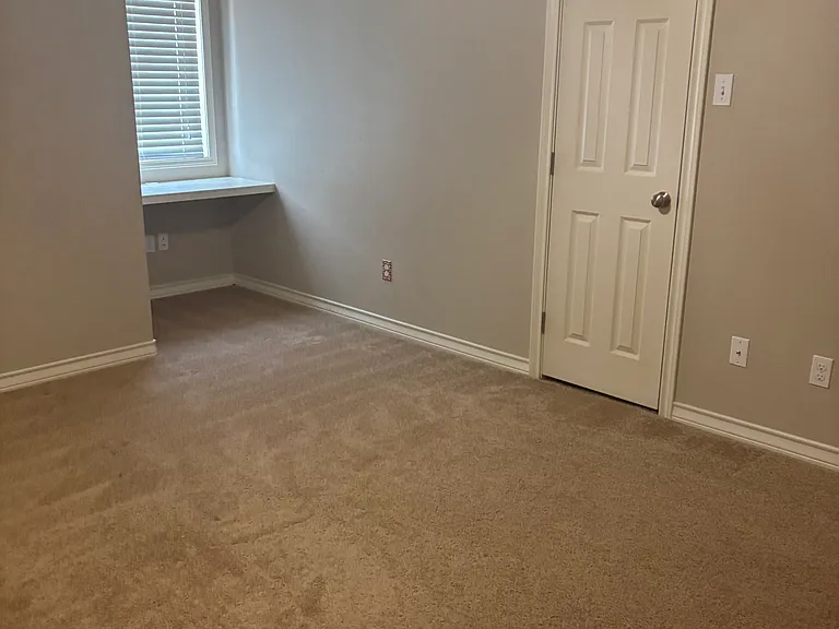 Bedroom number two with desk looking out front window. This room also has a large walk-in closet and wood blinds