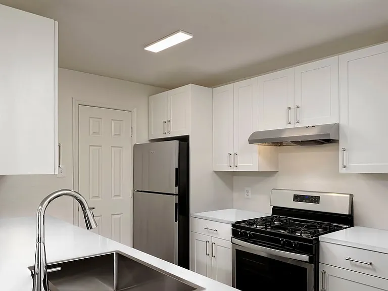 Updated kitchen with white cabinetry, white quartz countertops, stainless steel appliances, and hard surface flooring