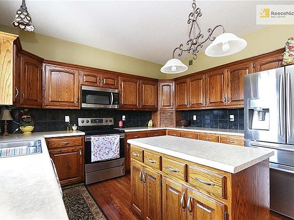 Kitchen has plenty of cabinets, center island and gleaming hardwood floors.