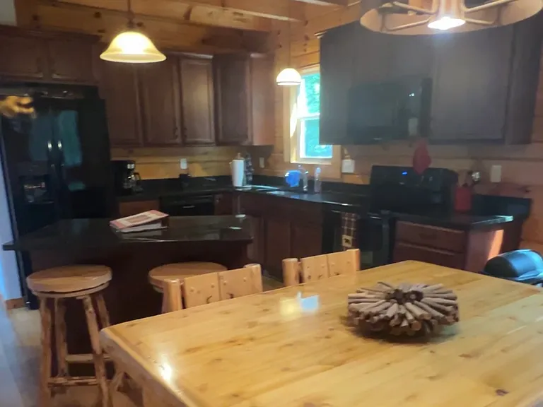 View of kitchen/dining area. There is plenty of cabinet space ,an island with storage space and 2 stools. We have glassware, dishes, utensils and a few other usable items for use. We have a stove, fridge, dishwasher, microwave, toaster, coffee maker .