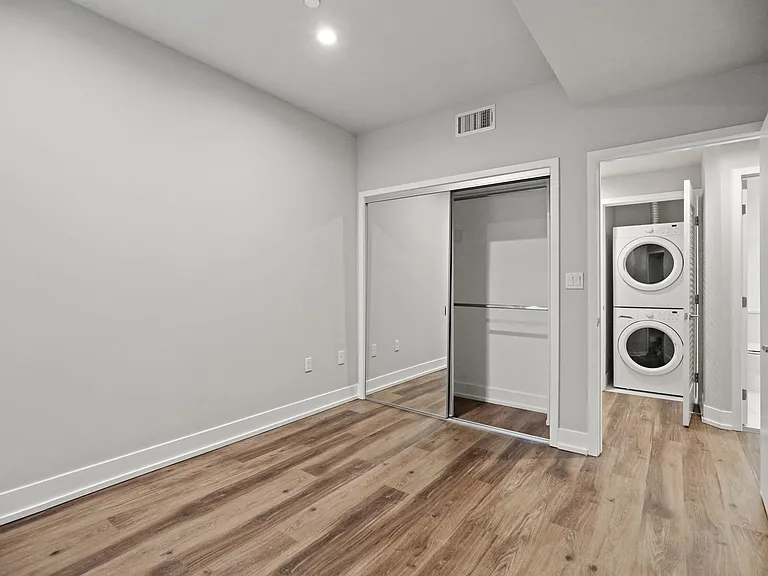 Bedroom with Mirrored Closet and Vinyl Flooring and Hallway with In-Suite Washer & Dryer