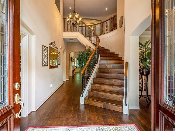 An impressive entry greets you as you enter the home with gleaming wood floors, a decorative iron railing and curved wood staircase leading to the second level of the home.