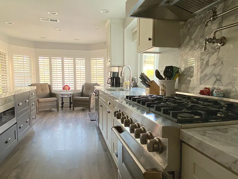 Cook like a pro in this chef's kitchen featuring a 36" six-burner gas range with a convenient pot filler. Marble countertops add elegance and style to your culinary space.