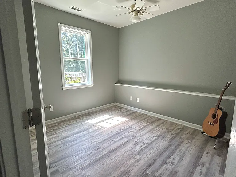 In our second bedroom, you'll find wide-plank hardwood floors, a ceiling fan, and big windows that let in lots of natural light. Each bedroom comes with a built-in wall shelf and coat hanger for easy organization.