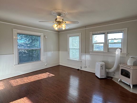 Living room is light and bright with multiple windows, gas-burning stove and AC window unit