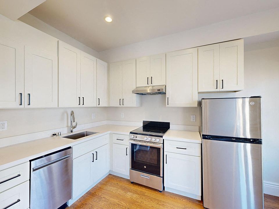 Kitchen with multiple cabinets, refrigerator, stove, range hood, and sink