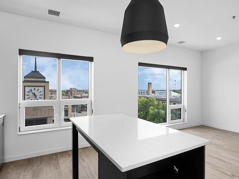 Bright modern kitchen with white countertops and large windows showcasing a stunning city view with a clock tower. Bright modern kitchen with white countertops and large windows showcasing a stunning city view with a clock tower.