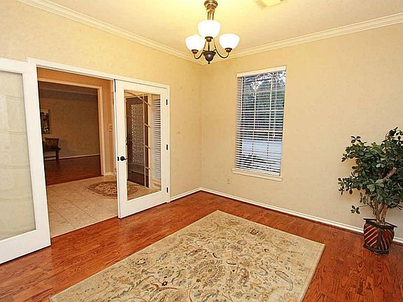 The dining room has an updated chandelier, crown molding, and a wood floor.