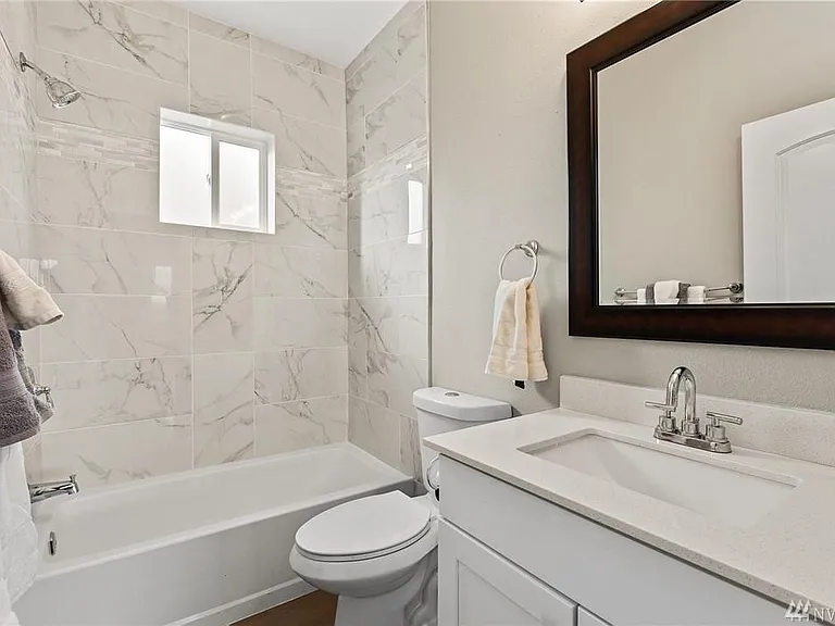Beautifully remodeled full bath on the main level featuring designer tile, a quartz vanity, and convenient access from the bedroom and main living areas.