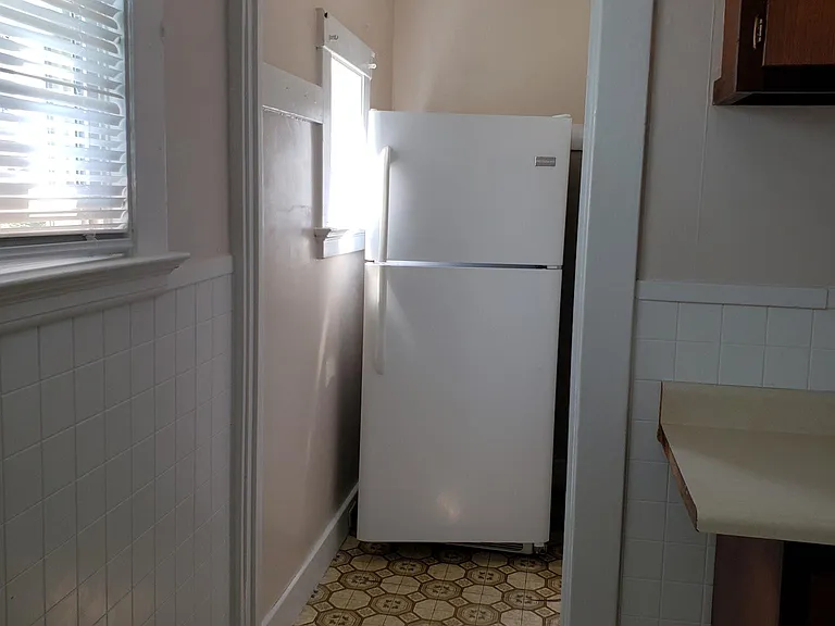 Another view of the kitchen along with image of the refrigerator and counter along the side with more overhead and below storage