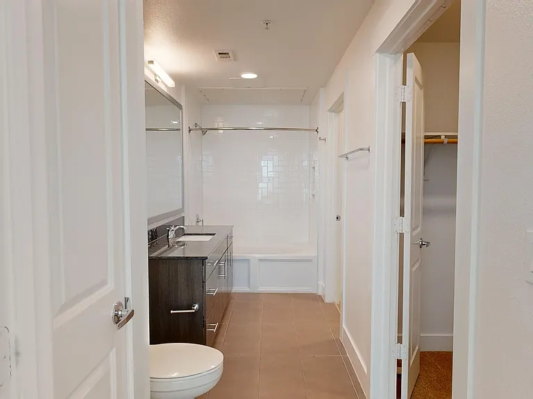 Apartment bathroom with large soaking tub and tile flooring.