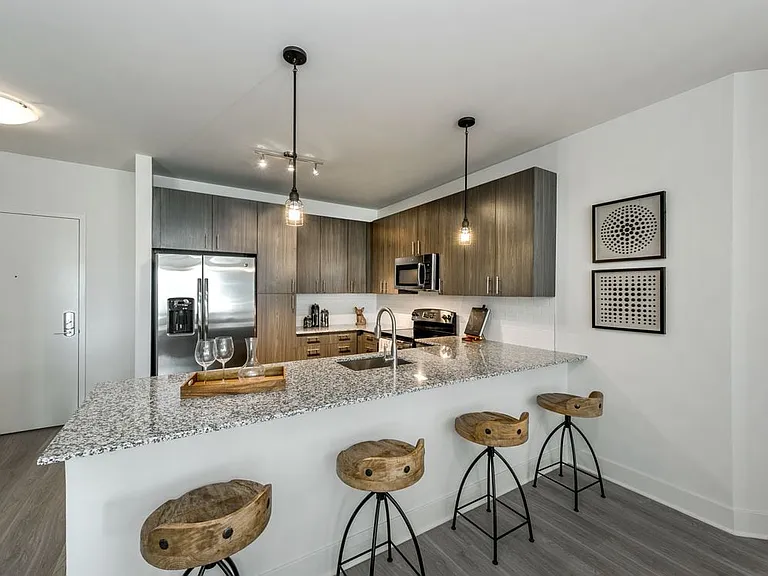 Open concept kitchen with brown cabinetry, granite countertops, stainless steel appliances, tile backsplash and hard surface flooring