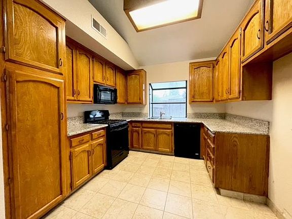 Kitchen with granite countertops, stainless steel sink.