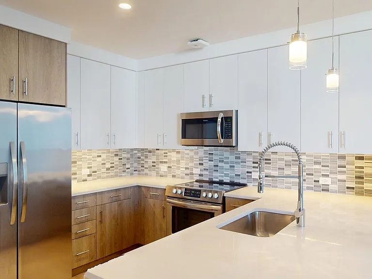 Apartment Kitchen with Quartz counter tops and Wood Style Flooring.