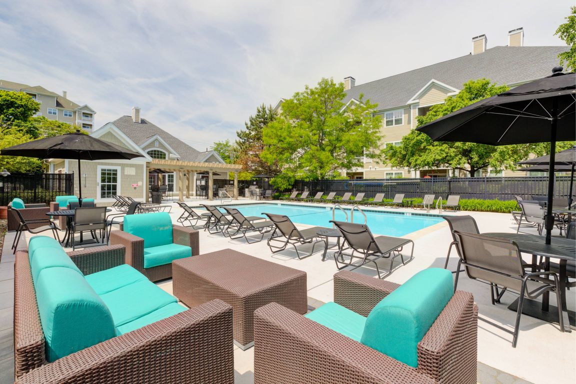 View of pool with soft seating, loungers, tables and umbrellas