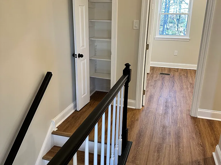 Bright upper-level landing at the top of the wood staircase_providing a seamless connection between living and bedroom areas with added space and versatility.