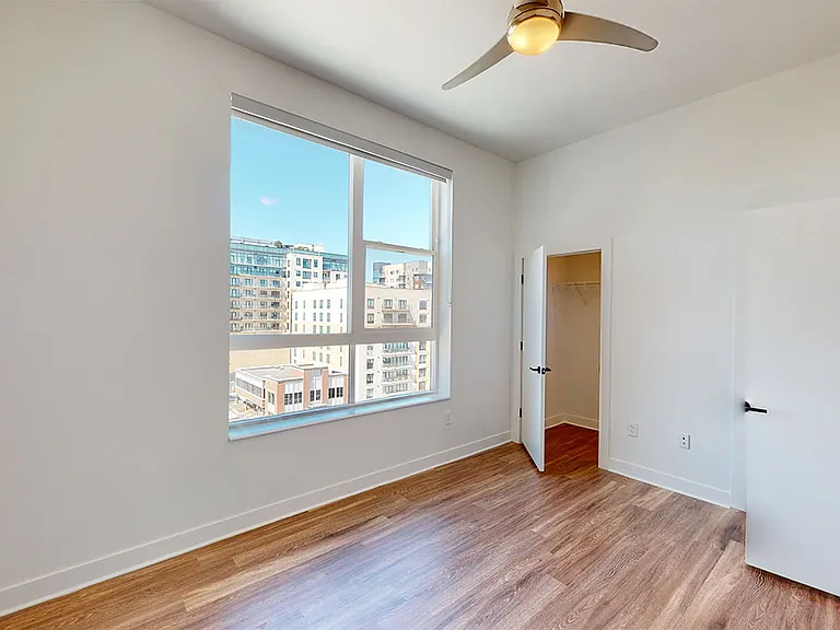Spacious apartment bedroom with large closet and wood-style flooring.