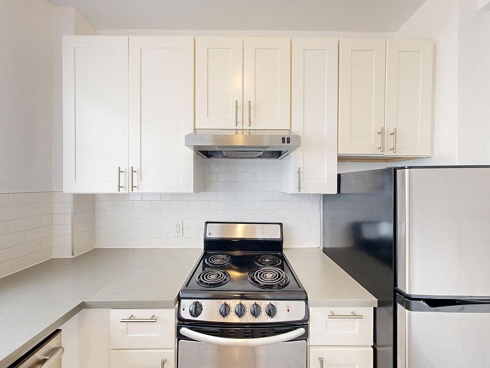 Kitchen with multiple cabinets, refrigerator, stove, and range hood