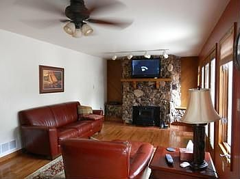 Large living room with woodburning fireplace & heatilator...plus nice bright shining wood floor, ceiling fan & large windows to view the back yard