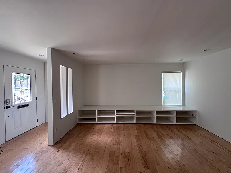 The living room features built-in storage for books and media as well as natural lighting from indirect sunlight. There is built-in recessed lighting as well.