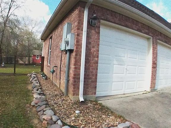BACK SIDE VIEW OF HOME WITH LOTS OF STONES FOR DRAINAGE AND RAIN GUTTERS.