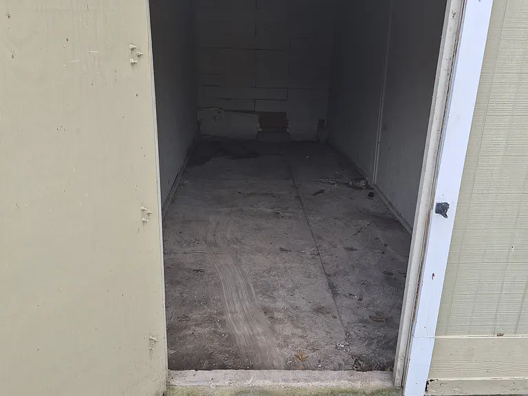 Outside storage unit with door open, looking in from parking lot.