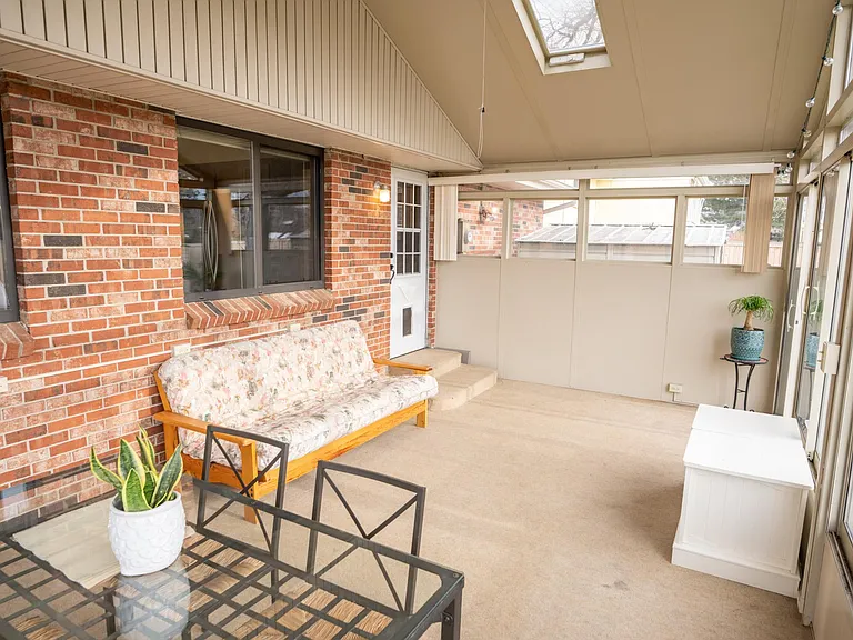 South-east view of the sun room. Entry into the house is in the far corner and out the windows, you can see one of the storage sheds and the back of the garage.