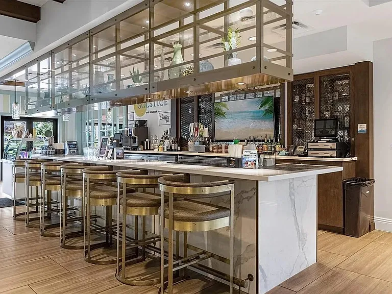 Stylish bar-style kitchen area with stone countertops, ample seating, and dedicated beverage station for easy entertaining.
