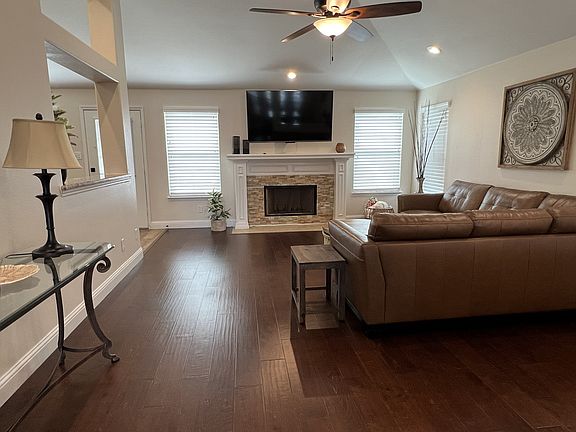 Spacious living room featuring vaulted ceilings, recessed lighting, and elegant stone fireplace.