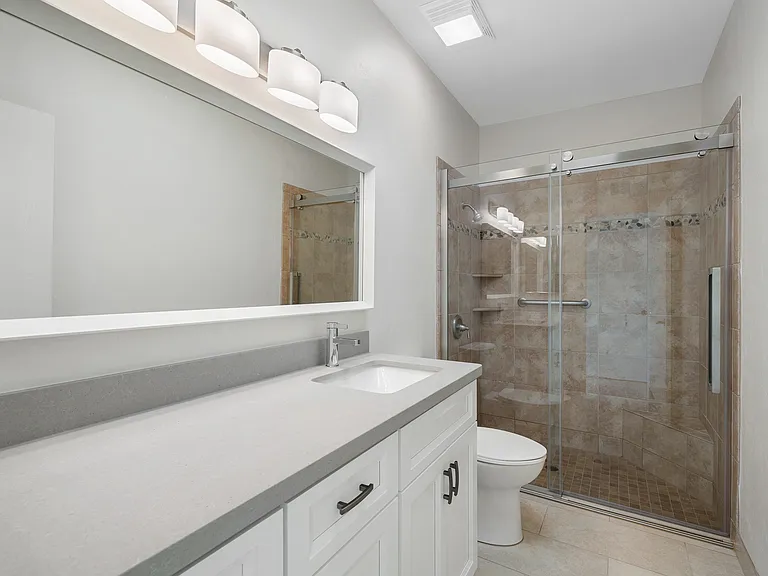 Primary Bath with new cabinets, quartz countertops and easy access rolling shower door