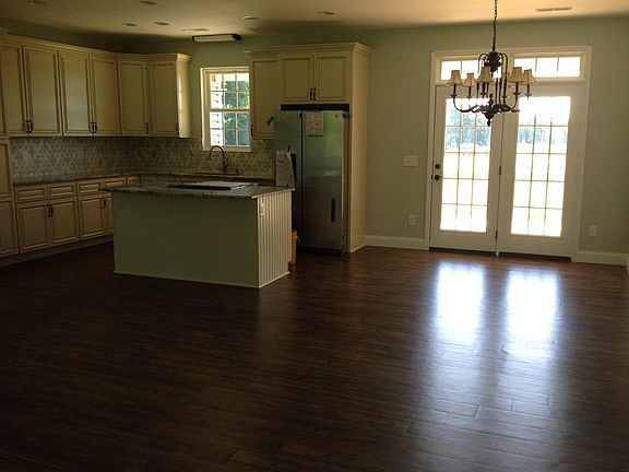 Stainless steel refrigerator, island with stove and dishwasher by the sink . Also a cabinet wall pantry .