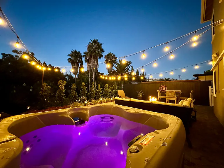 4 person hot tub, gas fire pit, outdoor seating, and outdoor dining table nestled in the canyon, with string lights and gorgeous views
