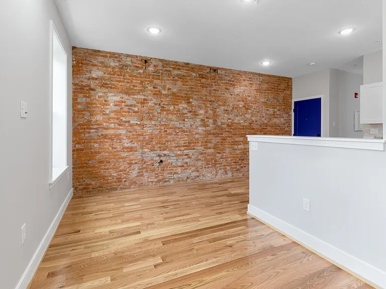 The living room has two large north-facing windows and is separated from the kitchen by a partition.