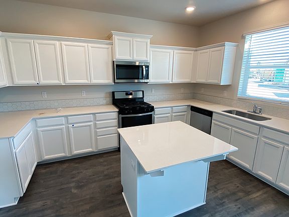 Modern kitchen includes stainless steel and high-efficiency appliances, a pantry closet, and modern quartz countertops