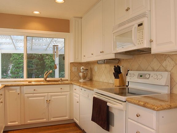 Upgraded kitchen with white cabinets and granite counters.