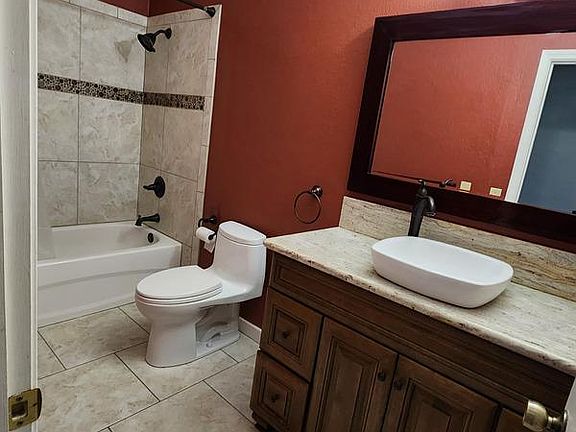 Large bathroom with full sized tub, rain shower, too toilet, tile and ample vanity.