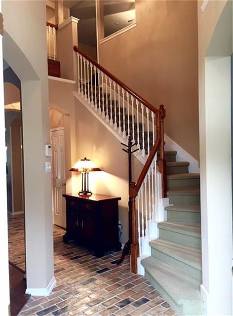 Inviting foyer featuring brick flooring, high ceilings and warm, neutral colors.