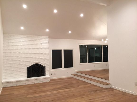 Living room with brick fireplace, high ceiling and plenty of natural light
