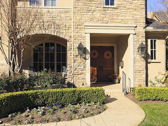A closer view of the covered porch and attractive stone/stucco exterior elevation. Professional landscaping. Graceful arches, porte cochere, curved entry way with stone pavers. Very welcoming!