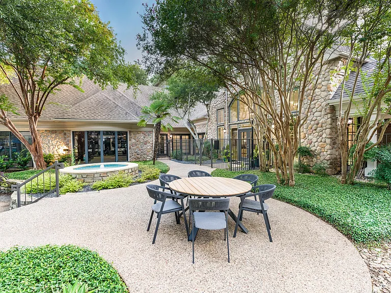 Shaded by mature trees and surrounded by stonework charm, this courtyard offers a welcoming spot to relax or catch up with neighbors.