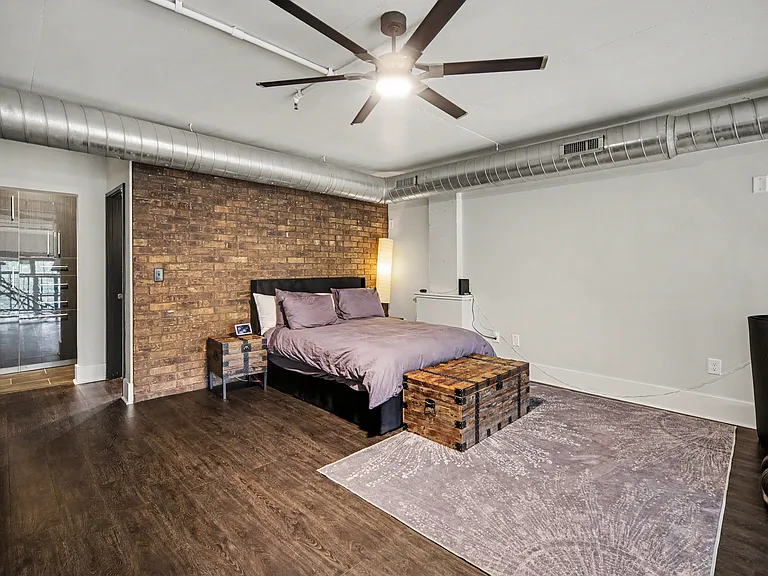 Master Bedroom with stunning brick accent wall, queen bed, 85" Samsung Smart TV, 5.1 sound system, Bowflex bench and adjustable weights up to 52.5 lbs per dumbbell, yoga matt, resistance bands and direct access to master bathroom and walk in closet