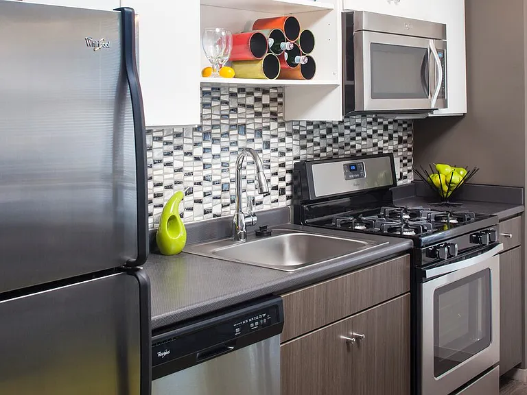 Classic Package II kitchen with stainless steel appliances, dark laminate countertops, white and brown cabinetry, tile backsplash, and hard surface flooring