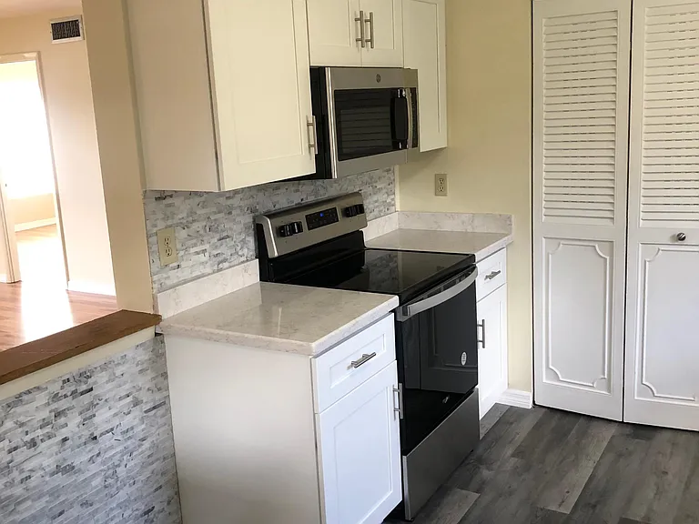 LUXURY GRADE VINYL FLOORING | SS MICROWAVE AND SMOOTH TOP COOKING UNIT | QUARTZ COUNTER TOPS | KITCHEN EAT SPACE AND STORAGE.