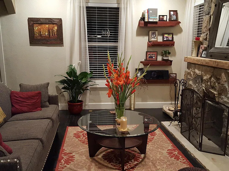 Living room decorated from the past when owner lived here. Window looks at porch swing. To the right is the side yard. Left is front door.