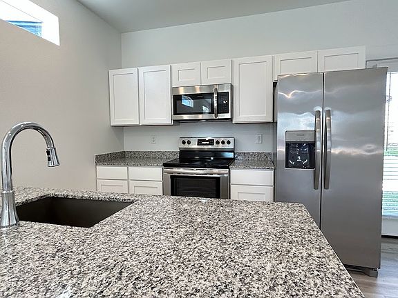 Kitchen has white wood cabinetry and brand new stainless steel appliances.